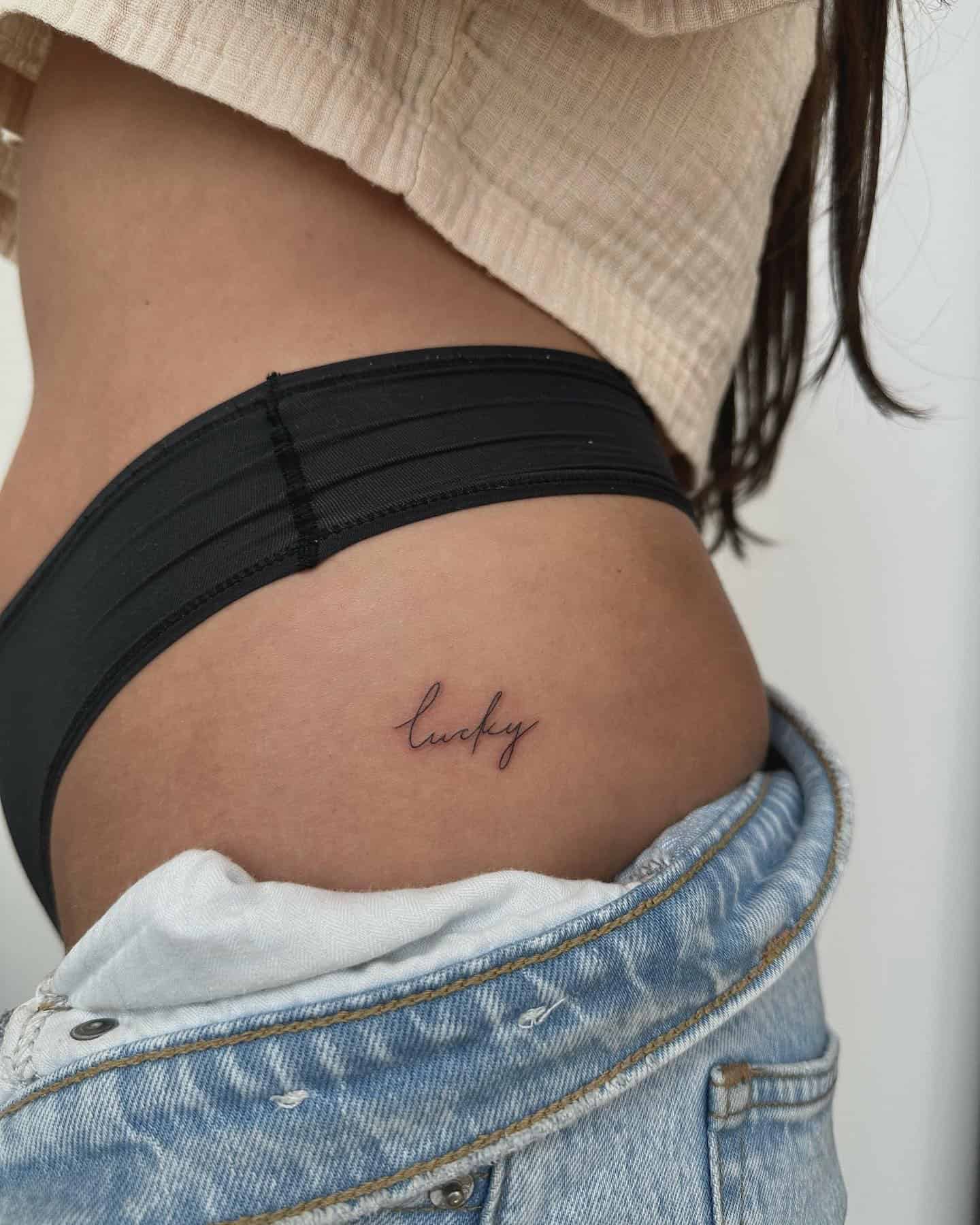 9] ‘Lucky’ Handwriting Hip Tattoo: Charm of Luck