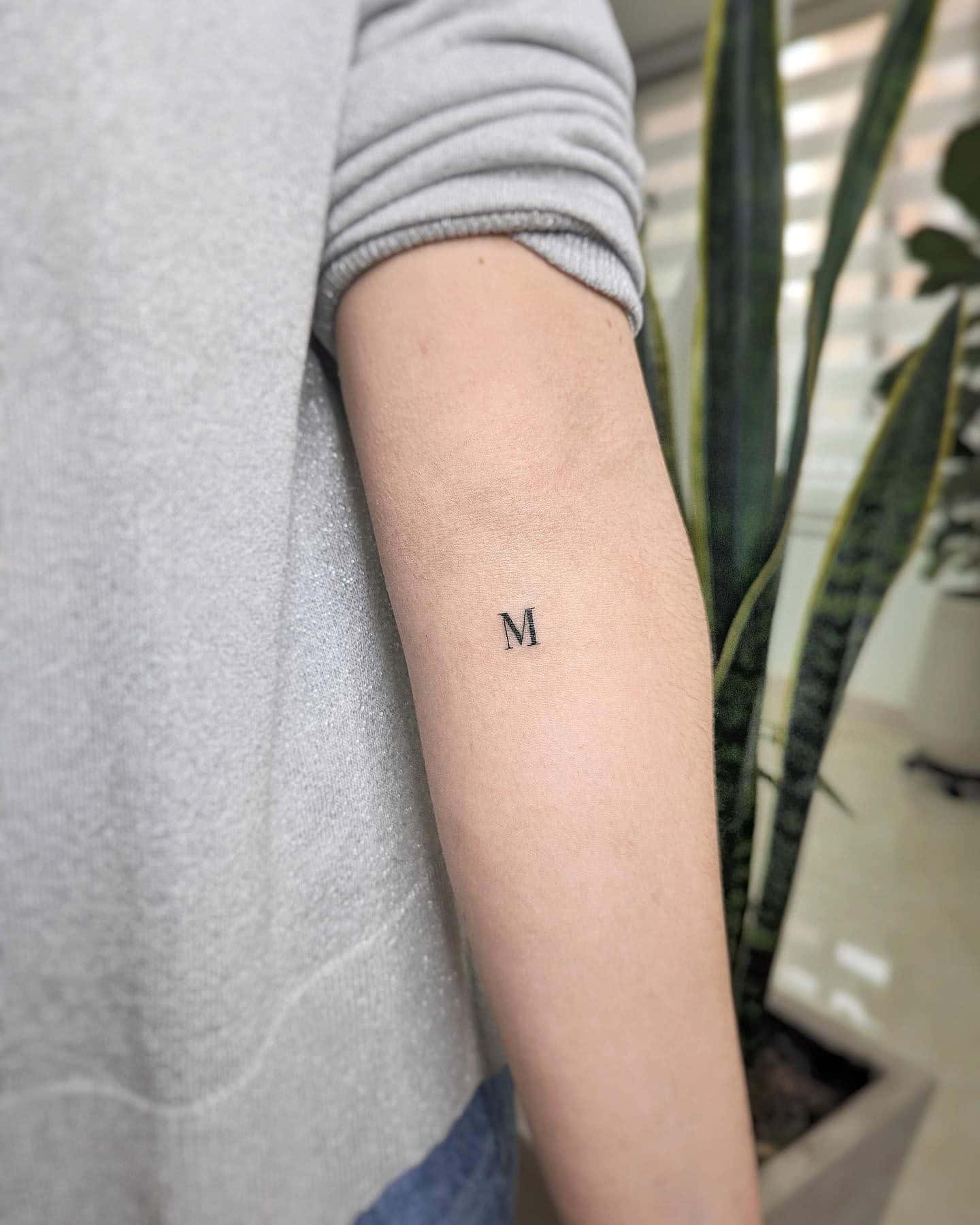 38] Classy ‘M’ Letter Tattoo: Forearm Adornment