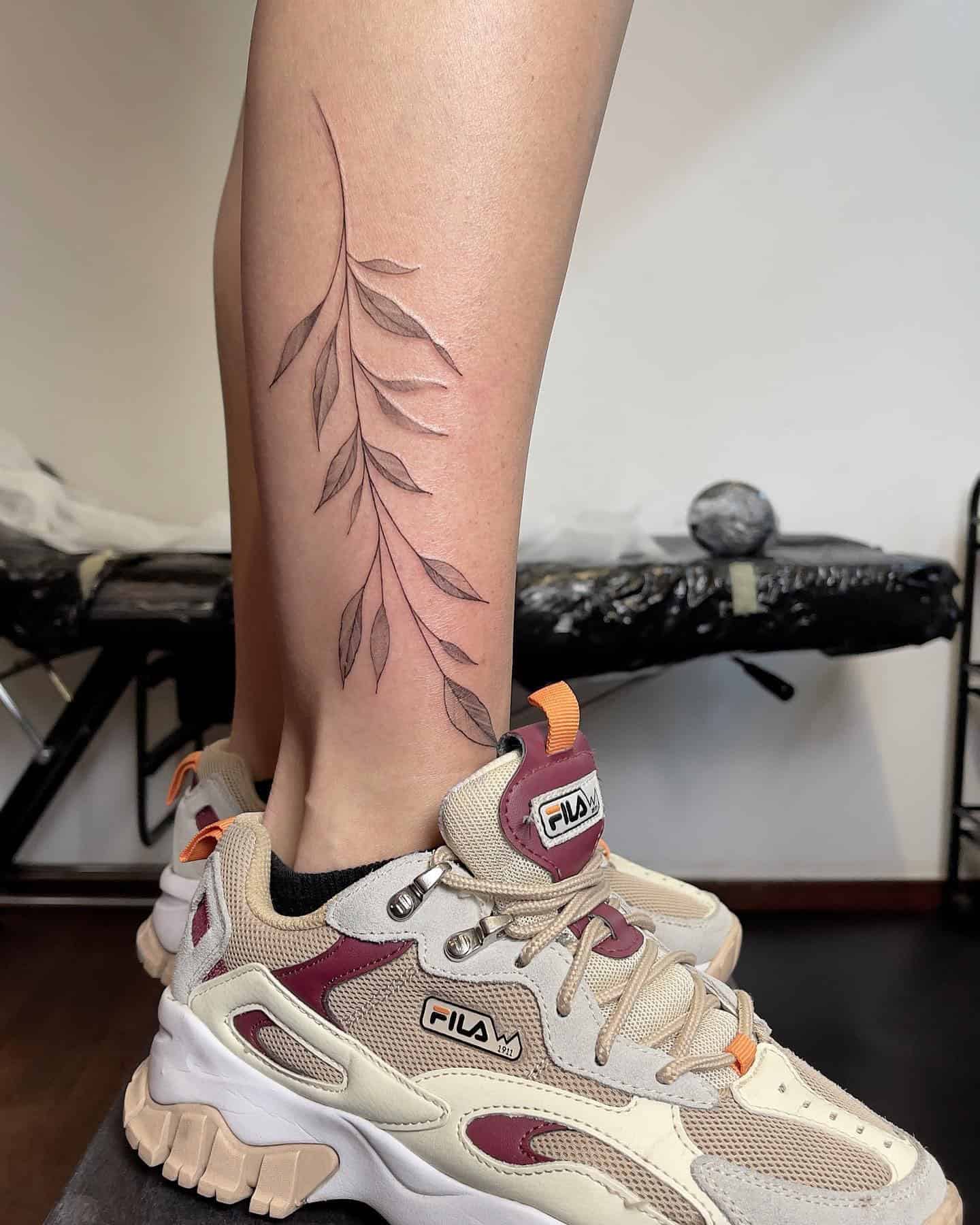 24] Dainty Willow Branch: A Leg Tattoo with Nature’s Grace